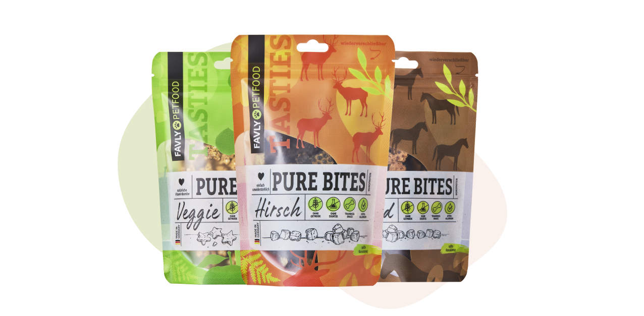 Drei Päckchen Favy Tiernahrung in verschiedenen Geschmacksrichtungen: Veggie, Hirsch und Mixed, mit bunten Tiermotiven.