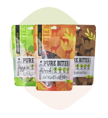Drei bunte Beutel Tierfutter mit der Aufschrift „PURE BITES“ und naturbezogenen Motiven.