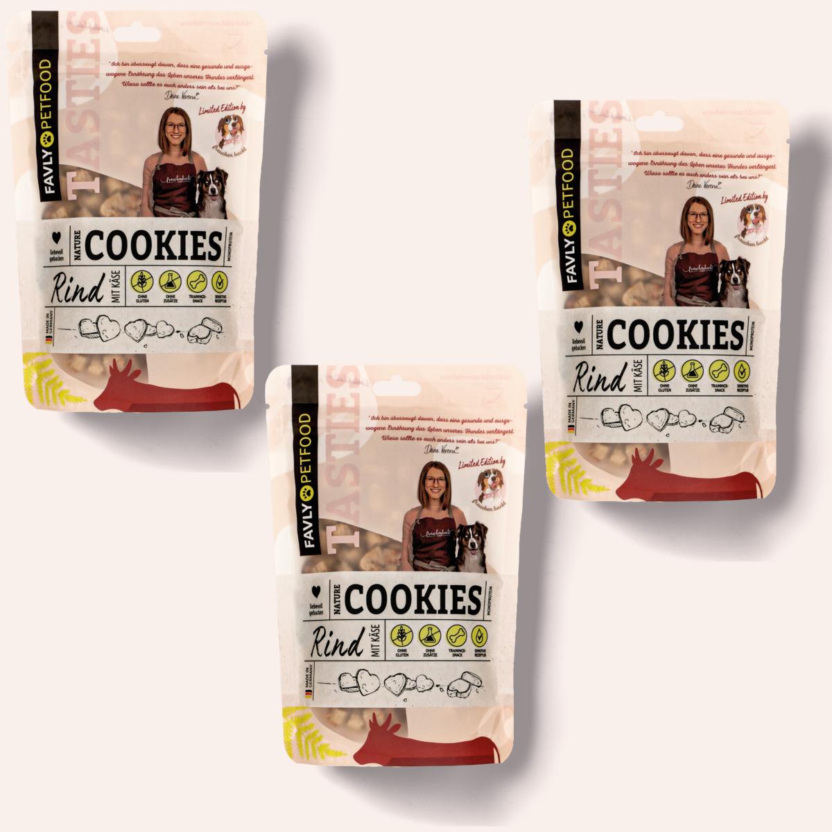Drei Packungen „Limited Edition - Nature Cookies @frauchen.backt“ Hundeleckerlis mit Rindfleischgeschmack von FAVLY Petfood, hergestellt aus natürlichen Zutaten und mit einer Frau mit zwei Hunden auf der Verpackung. Die perfekten Hundesnacks für Ihre pelzigen Freunde!