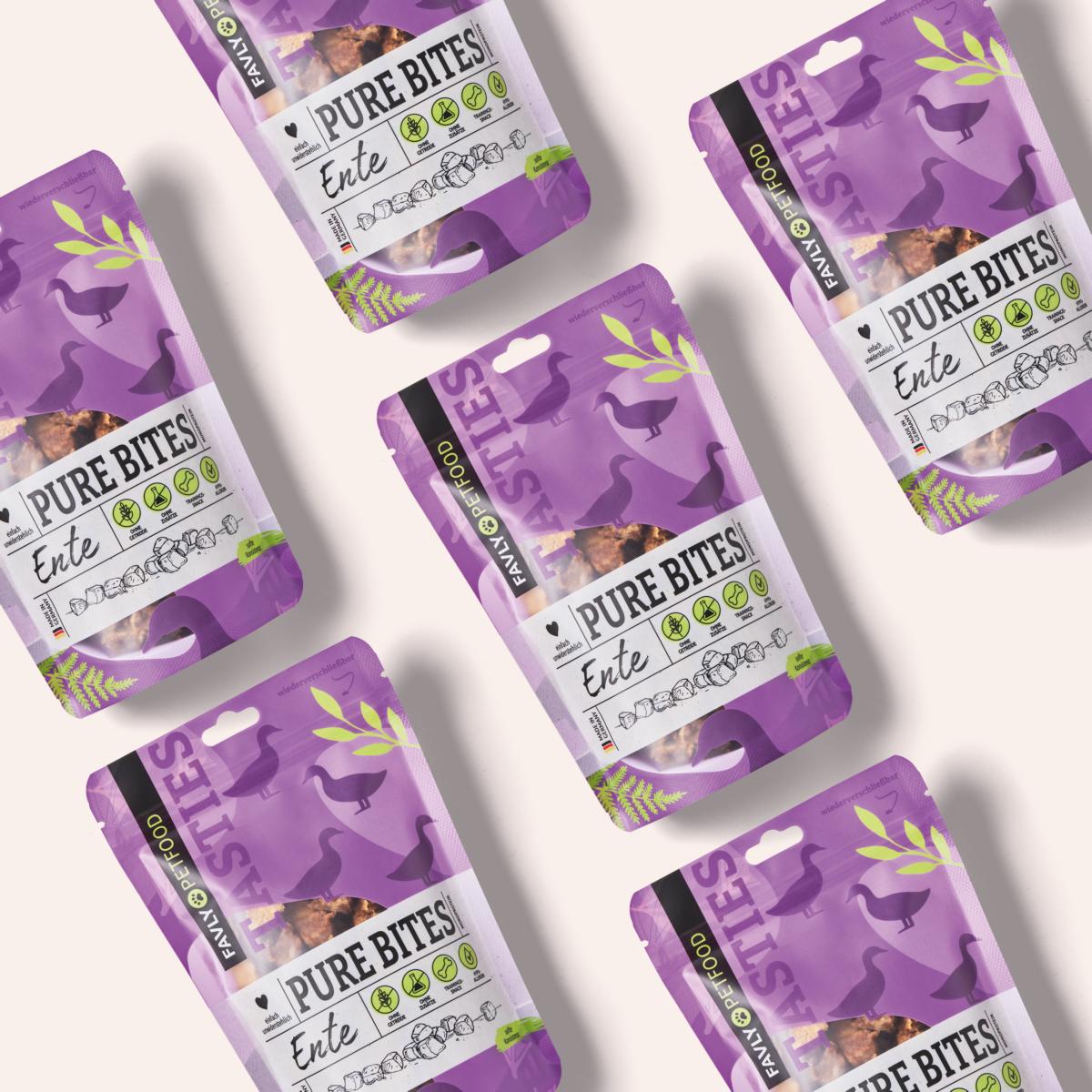 Flache Anordnung mehrerer violetter und grüner Packungen „PURE Bites Ente“, Hundesnacks mit Entengeschmack von FAVLY Petfood, hergestellt aus natürlichen Zutaten, auf hellem Hintergrund.
