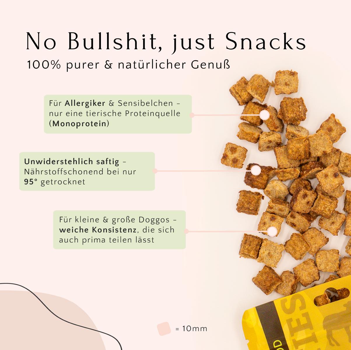 Verstreut liegen gold-braune quadratische Hundeleckerlis aus dem FAVLY Probierpaket „Starter“ von FAVLY Petfood, deren deutscher Text auf die natürlichen Zutaten, den Monoproteingehalt und die Hundefreundlichkeit hinweist.