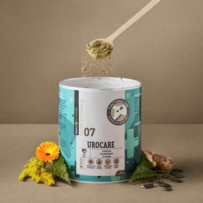 Ein Holzlöffel streut grüne UROCARE Pulver - Niere & Blase von FAVLY Petfood, Kräuter und Blumen daneben.