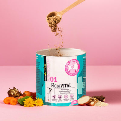 Ein Löffel FAVLY Petfood FloraVITAL Pulver - Verdauung & Darmflora inmitten von Kräutern auf Pink, für die Darmgesundheit.