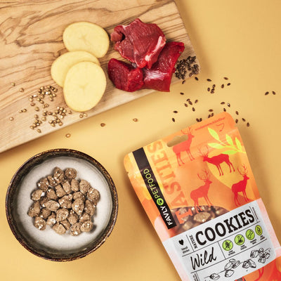 Nature Cookies Wild von FAVLY Petfood mit Beef & Potato auf Holzbrett und im Napf vor gelber Verpackung.