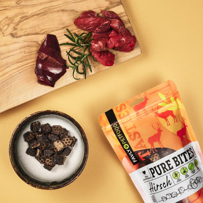 Schale mit FAVLY Petfood PURE Bites Hirsch Hundesnacks und natürlichen Zutaten auf Holzbrett.