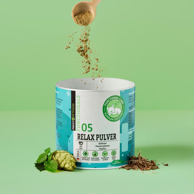 Eine Hand streut FAVLY Petfood Relax Pulver - Unruhe & Stress in einen Behälter auf grünem Hintergrund.